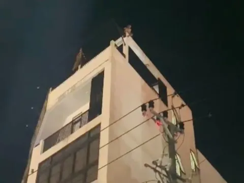 Một người có biểu hiện mất kiểm soát ngồi trên nóc tòa nhà 4 tầng